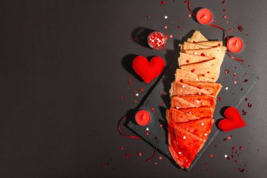 Romantik kahvaltı fikri, kırmızı krep ya da tatlı kalpler üzerine ince krepler. Sevgililer Günü ya da Anneler Günü için kutlama yemeği. Modaya uygun sert ışık, karanlık gölge. Siyah taş arkaplan, üst görünüm