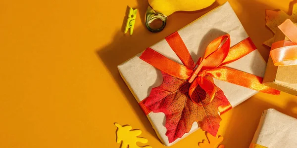 秋の色でギフトの概念 包装された箱 お祝いの秋の装飾 カボチャ および果実 流行のハードライト 暗い影 オレンジの背景 バナー形式 — ストック写真