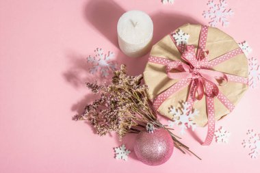 Noel ya da yeni yıl hediyesi konsepti pembe tonlarda. Paket kutusu, bağlı fiyonk, kuru çiçekler ve şenlikli oyuncak. Sıfır Atık Tarzı, modaya uygun sert ışık, koyu gölge, pembe arkaplan, üst görünüm