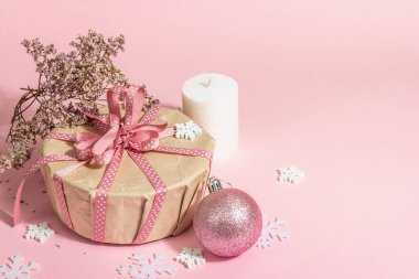 Noel ya da yeni yıl hediyesi konsepti pembe tonlarda. Paket kutusu, bağlı fiyonk, kuru çiçekler ve şenlikli oyuncak. Sıfır Atık Biçimi, modaya uygun sert ışık, koyu gölge, pembe arkaplan, kopyalama alanı