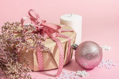 Noel ya da yeni yıl hediyesi konsepti pembe tonlarda. Paket kutusu, bağlı fiyonk, kuru çiçekler ve şenlikli oyuncak. Sıfır Atık Tarzı, modaya uygun sert ışık, koyu gölge, pembe arkaplan, kapat