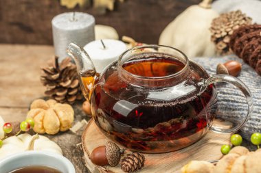 Sonbahar çayı konsepti. Balkabaklı kurabiye, çaydanlıkta siyah çay, sonbahar dekoru. Çelenk, mumlar, rahat bir kazak. Eski tahta arkaplan, kopyalama alanı