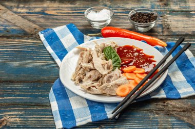 Baharatlı sos ve sebzeli haşlanmış tavuk eti. Düşük yağlı hayvan proteini, sağlıklı besin yaşam tarzı. Ahşap arka planda çatal bıçak ve keten peçete, kopyalama alanı