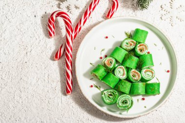 Soğuk meze, Noel ağacı şeklinde süslenmiş. İnce krep, krem peynir, hafif tuzlu somon, yeşiller, modaya uygun sert ışık, koyu gölge. Şenlikli Yeni Yıl dekorasyonu, macun arkaplan, üst görünüm