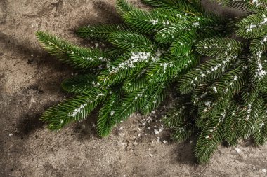 Taş beton zemin üzerinde köknar dallarından yapılmış Mutlu Noeller çelengi. Xmas ve yeni yıl tatili, modern aydınlık, karanlık gölge. Yapay kar, düz yatış, üst görünüm