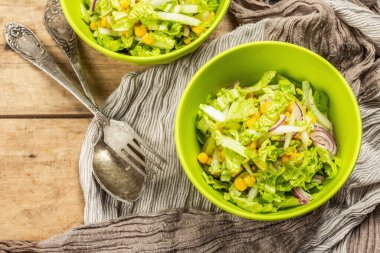 Çin lahanasından lezzetli vejetaryen salatası, tatlı mısır, mor soğan ve sos. Ahşap zemin, çatal bıçak takımı, eski peçete, kırsal stil, üst manzara.