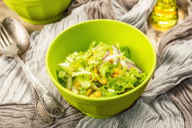 Çin lahanasından lezzetli vejetaryen salatası, tatlı mısır, mor soğan ve sos. Ahşap arka plan, çatal bıçak takımı, eski peçete, kırsal stil, kapat.