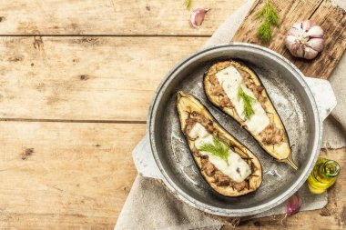 Doldurulmuş patlıcan, et, sebze ve baharatla birlikte yenmeye hazır. Ahşap zemin, mutfak gereçleri, kırsal stil, üst manzara.