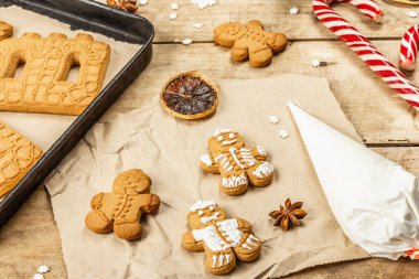 Zencefilli kurabiye adamlar tatlı krema süsler. Geleneksel şenlik dekorasyonu, yemek pişirme süreci. Eski ahşap arka plan, ev yapımı konsept, yakın plan.