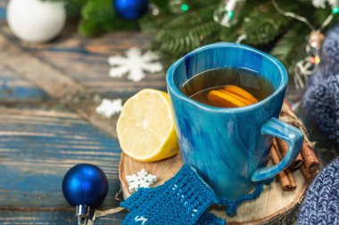 Tığ işi komik eldivenli sıcak içecek. Geleneksel kış dekoru, köknar ağacı dalları, kar taneleri. Mavi tonlarda şenlikli sezonluk düzenleme, eski ahşap arka plan, yakın plan.