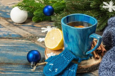 Tığ işi komik eldivenli sıcak içecek. Geleneksel kış dekoru, köknar ağacı dalları, kar taneleri. Mavi tonlarda şenlikli mevsimsel düzenleme, eski ahşap arka plan, kopyalama alanı