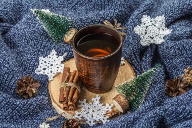 Geleneksel yeni yıl dekorasyonuyla seramik fincanda siyah çay. Küçük köknar, örülmüş kar taneleri, tarçın ve koniler. Ahşap tezgah, rahat örgü süveter düzenleme, kopyalama alanı