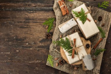 Sıfır atık hediye konsepti. Noel ya da yeni yıl çevre dostu paketleme. Farklı organik süslemeleri olan el sanatları kağıdındaki kutular. Vintage ahşap arkaplan, üst görünüm