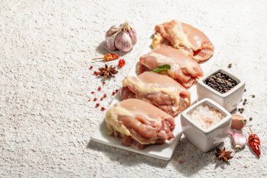 Kemiksiz ve derisiz çiğ tavuk budu. Sağlıklı yemek, baharat ve sarımsak hazırlamak için kullanışlı bir malzeme. Moda sert ışığı, karanlık gölge, aydınlık macun arkaplanı, kopyalama alanı