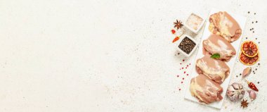 Kemiksiz ve derisiz çiğ tavuk budu. Sağlıklı yemek, baharat ve sarımsak hazırlamak için kullanışlı bir malzeme. Hafif macun arkaplanı, üst görünüm, pankart biçimi