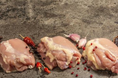 Kemiksiz ve derisiz çiğ tavuk budu. Sağlıklı yemek, baharat ve sarımsak hazırlamak için kullanışlı bir malzeme. Koyu taş arkaplan, boşluğu kopyala