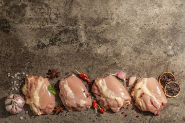 Kemiksiz ve derisiz çiğ tavuk budu. Sağlıklı yemek, baharat ve sarımsak hazırlamak için kullanışlı bir malzeme. Koyu taş arkaplan, üst görünüm