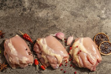Kemiksiz ve derisiz çiğ tavuk budu. Sağlıklı yemek, baharat ve sarımsak hazırlamak için kullanışlı bir malzeme. Koyu taş arkaplan, üst görünüm