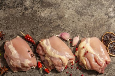 Kemiksiz ve derisiz çiğ tavuk budu. Sağlıklı yemek, baharat ve sarımsak hazırlamak için kullanışlı bir malzeme. Koyu taş arkaplan, üst görünüm