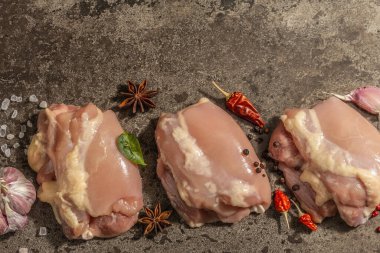 Kemiksiz ve derisiz çiğ tavuk budu. Sağlıklı yemek, baharat ve sarımsak hazırlamak için kullanışlı bir malzeme. Koyu taş arkaplan, üst görünüm