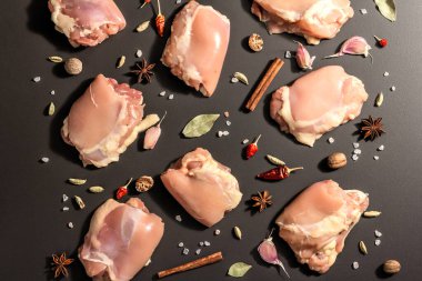 Kemiksiz ve derisiz çiğ tavuk butları. Sağlıklı yemek, baharat ve sarımsak hazırlamak için kullanışlı bir malzeme. Siyah taş arka plan, modaya uygun sert ışık, karanlık gölge, üst görüş