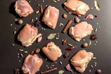 Kemiksiz ve derisiz çiğ tavuk butları. Sağlıklı yemek, baharat ve sarımsak hazırlamak için kullanışlı bir malzeme. Siyah taş arka plan, modaya uygun sert ışık, karanlık gölge, üst görüş