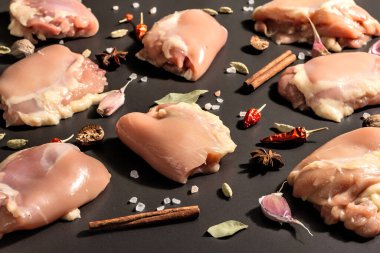 Kemiksiz ve derisiz çiğ tavuk butları. Sağlıklı yemek, baharat ve sarımsak hazırlamak için kullanışlı bir malzeme. Siyah taş arka plan, modaya uygun sert ışık, karanlık gölge, kapat