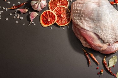 Baharatlı çiğ hindi eti. Sağlıklı yemek, baharat ve sarımsak hazırlamak için kullanışlı bir malzeme. Modern sert ışık, karanlık gölge, siyah taş arkaplan, üst görünüm