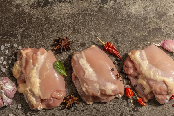 Kemiksiz ve derisiz çiğ tavuk budu. Sağlıklı yemek, baharat ve sarımsak hazırlamak için kullanışlı bir malzeme. Koyu taş arkaplan, üst görünüm
