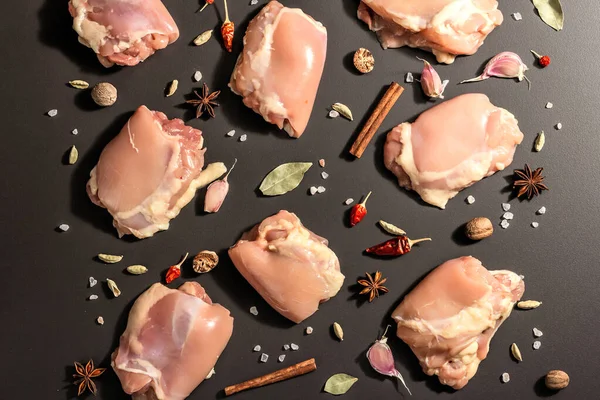 Kemiksiz ve derisiz çiğ tavuk butları. Sağlıklı yemek, baharat ve sarımsak hazırlamak için kullanışlı bir malzeme. Siyah taş arka plan, modaya uygun sert ışık, karanlık gölge, üst görüş