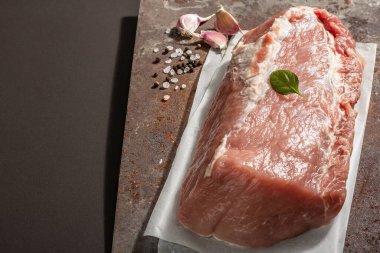 Baharatlı çiğ domuz filetosu. Paslı metal standında büyük bir parça et, siyah taş beton arka plan. Moda sabit ışık, karanlık gölge, boşluğu kopyala