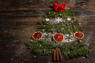 Bitmeyen yeşil dallardan, kurutulmuş limon dilimlerinden ve kar tanelerinden gelen yaratıcı köknar ağacı. Ahşap zemin, düz döşeme, şenlikli dekor, üst manzara