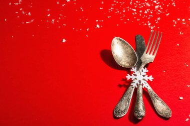 Yılbaşı sofrası kırmızı tonlarda ve kaliteli çatal bıçaklarla dolu. Yeni Yıl Şenliği, Kart Şablonu. Modern sert ışık, karanlık gölge. Düz konum, kırmızı arkaplan, kopyalama alanı
