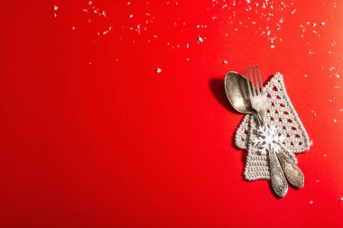 Yılbaşı sofrası kırmızı tonlarda ve kaliteli çatal bıçaklarla dolu. Yeni Yıl Şenliği, Kart Şablonu. Modern sert ışık, karanlık gölge. Düz konum, kırmızı arkaplan, üst görünüm