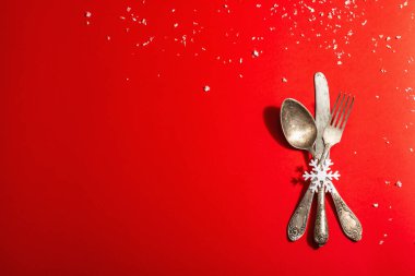 Yılbaşı sofrası kırmızı tonlarda ve kaliteli çatal bıçaklarla dolu. Yeni Yıl Şenliği, Kart Şablonu. Modern sert ışık, karanlık gölge. Düz konum, kırmızı arkaplan, üst görünüm