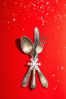 Yılbaşı sofrası kırmızı tonlarda ve kaliteli çatal bıçaklarla dolu. Yeni Yıl Şenliği, Kart Şablonu. Modern sert ışık, karanlık gölge. Düz konum, kırmızı arkaplan, üst görünüm