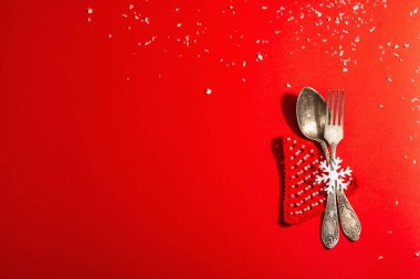 Yılbaşı sofrası kırmızı tonlarda ve kaliteli çatal bıçaklarla dolu. Yeni Yıl Şenliği, Kart Şablonu. Modern sert ışık, karanlık gölge. Düz konum, kırmızı arkaplan, üst görünüm