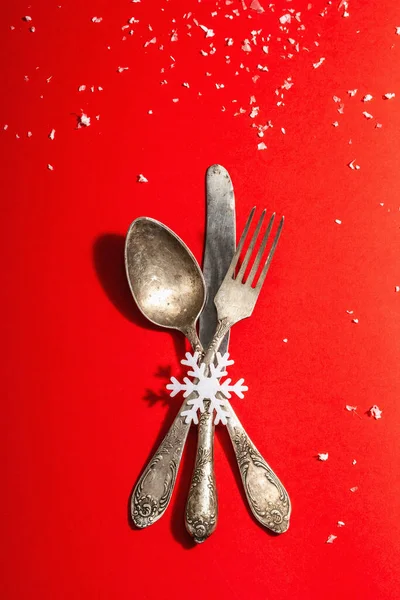 Yılbaşı sofrası kırmızı tonlarda ve kaliteli çatal bıçaklarla dolu. Yeni Yıl Şenliği, Kart Şablonu. Modern sert ışık, karanlık gölge. Düz konum, kırmızı arkaplan, üst görünüm
