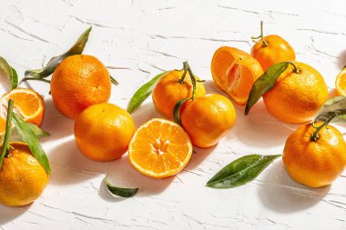 Yeşil yapraklı mandalina (portakal, mandalina, mandalina, narenciye). Modern sert ışık, karanlık gölge. Beyaz macun arkaplan, yaratıcı düz yatak, yakın çekim
