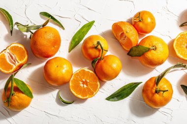 Yeşil yapraklı mandalina (portakal, mandalina, mandalina, narenciye). Modern sert ışık, karanlık gölge. Beyaz macun arkaplan, yaratıcı düz yatak, üst görünüm