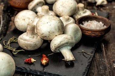 Baharatlı ve otlu taze şampiyonlar. Vejetaryen yemeği pişirmek için ham malzeme. Eski ahşap arka plan, modaya uygun aydınlık, karanlık gölge, kırsal tarz, yakın çekim.