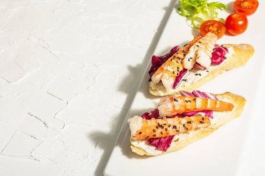Open sandwiches with boiled shrimps, cream cheese, salad leaves and cherry tomatoes. Seafood, healthy food. White putty background, trendy hard light, dark shadow, top view