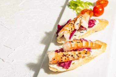 Open sandwiches with boiled shrimps, cream cheese, salad leaves and cherry tomatoes. Seafood, healthy food. White putty background, trendy hard light, dark shadow, copy space