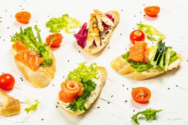 Assorted open sandwiches with salted salmon, boiled shrimps, cream cheese, salad leaves and cherry tomatoes. Seafood, healthy food. White putty background, creative flat lay, close up