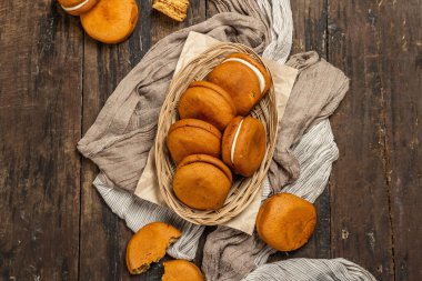 Homemade honey biscuits stuffed cream. Sweet dessert, indispensable ingredient for tea time. Old wooden background, top view