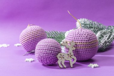 Crocheted Christmas balls and festive New Year decor in a fashion lilac very peri color. Winter greeting card, trendy hard light, dark shadow. Violet matte background, copy space