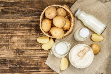 Alternatif patates sütü, güncel sütsüz içecek. Laktozsuz vejetaryen bitki içeceği, sebze ve kuru toz. Ahşap arkaplan, üst manzara