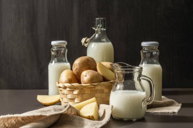 Alternatif patates sütü, güncel sütsüz içecek. Laktozsuz vejetaryen bitki içeceği, sebze ve kuru toz. Modern sert ışık, karanlık gölge, siyah taş arkaplan, kopyalama alanı