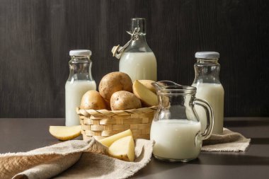 Alternatif patates sütü, güncel sütsüz içecek. Laktozsuz vejetaryen bitki içeceği, sebze ve kuru toz. Modern sert ışık, karanlık gölge, siyah taş arkaplan, kopyalama alanı