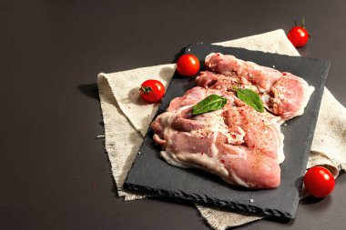 Çiğ hindi budu ve baharat. Seramik tezgahta taze kemiksiz et. Modern sert ışık, karanlık gölge. Siyah taş arkaplan, boşluğu kopyala